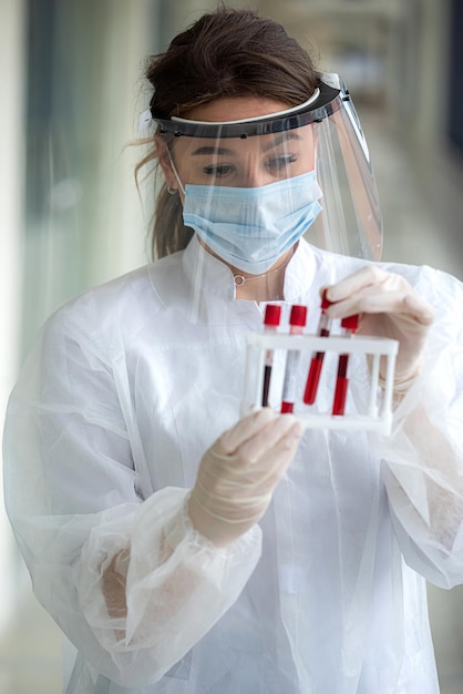 Nurse wearing scrubs holding and looking at blood test tube in lab