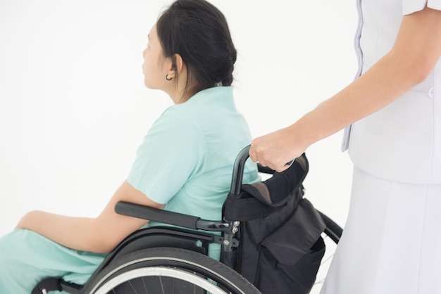 Nurse white uniform pushing a wheelchair of patient green suit 