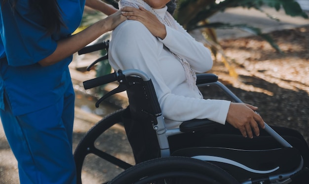 nurse with elderly man in wheelchair at park