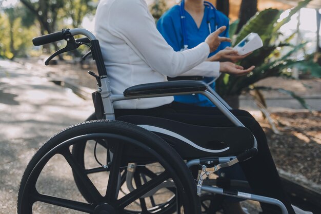 nurse with elderly man in wheelchair at park