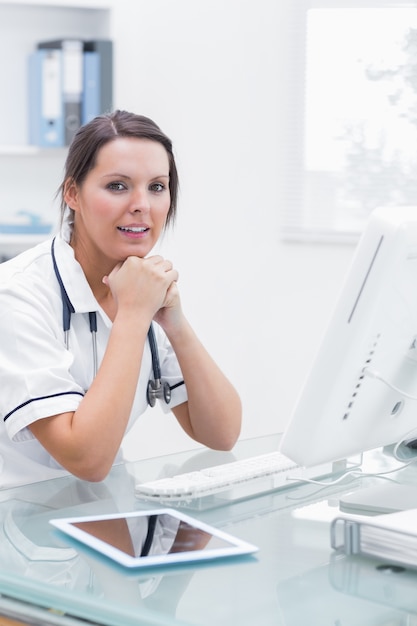 Foto infermiere con le mani sotto il mento davanti al computer in clinica