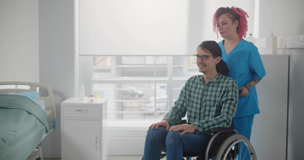 病院で車椅子に座っている患者を持つ看護師
