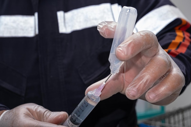 写真 保護手袋をかぶった看護師がプラスチック製のアンプールから抗炎症剤を取り除いています