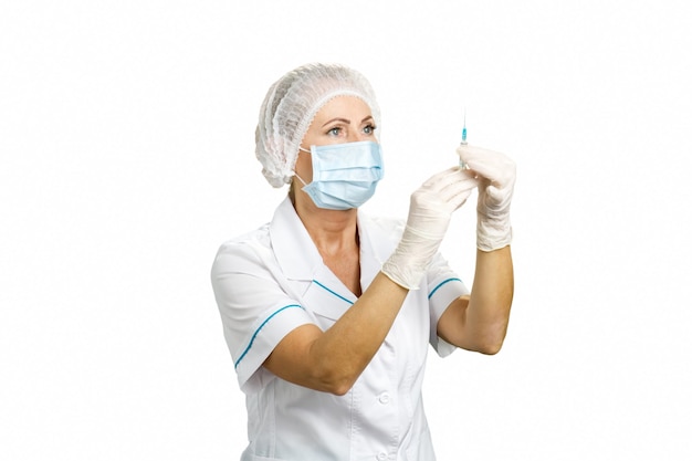 Photo nurse with protective mask holding injection. close up of female mature doctor holding syringe with injection on white. healthcare and medical concept.