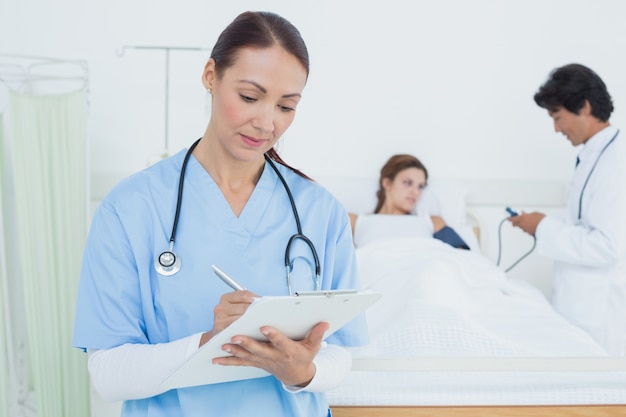 Nurse writing on medical chart