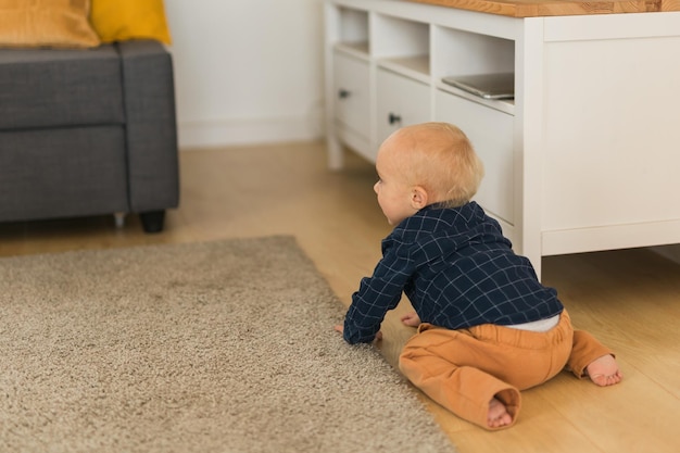 Фото Детский мальчик ползает по полу в помещении дома, копирует пространство и пустое место для текста, детское любопытство