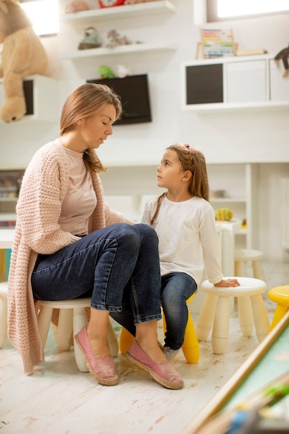 Insegnante di scuola materna che parla con una bambina carina con un problema all'asilo