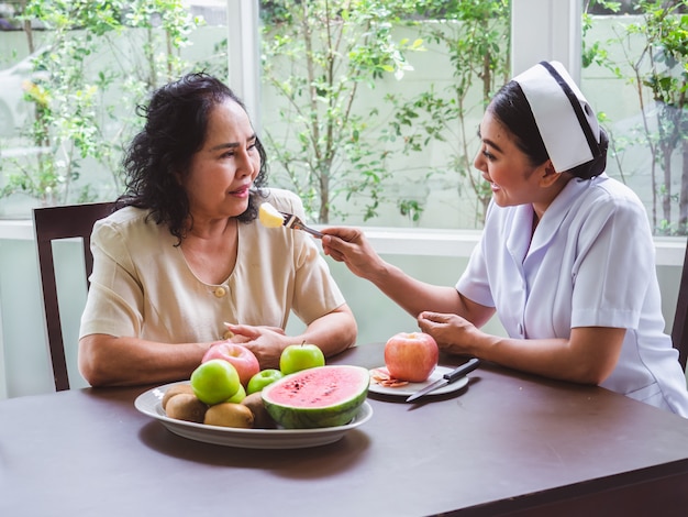 Медсестры кормят яблоки для пожилых людей