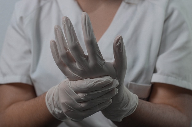 Photo nursing assistant putting on protective gloves