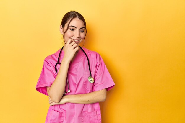 Nursing assistant in yellow background relaxed thinking about something looking at a copy space