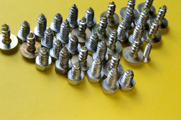 Nut bolts and selftapping screws of different sizes lie on a yellow background closeup