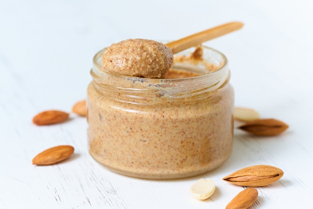 Nut butter, crunchy and stir, white wooden table, glass jar