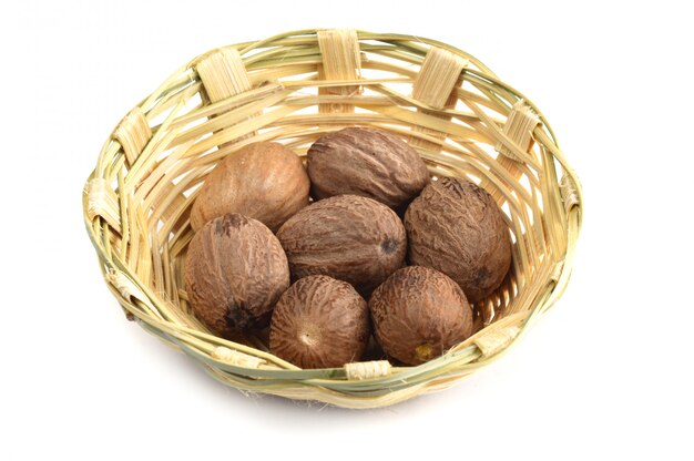 Nutmeg in bamboo basket isolated on white background