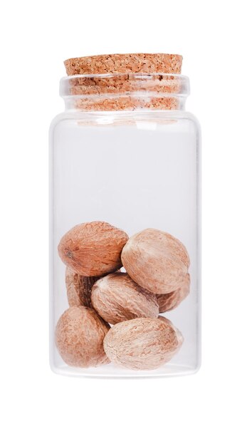 Nutmeg in a glass bottle with cork stopper isolated on white