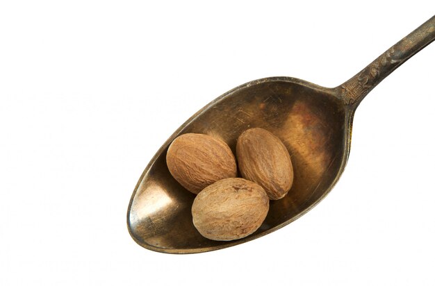 Nutmeg in an old spoon on a white background. 