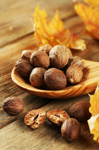 Nutmeg in wooden spoon on table close up