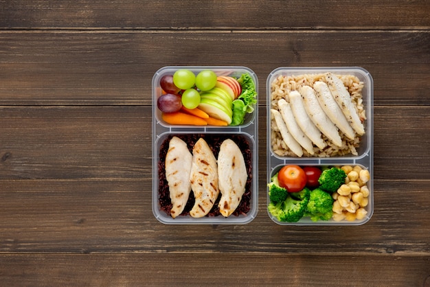 Nutrient rich healthy low fat food in takeaway meal box sets on wood background top view with copy space