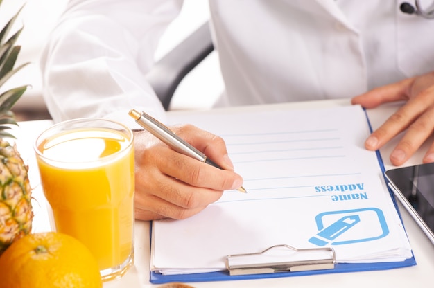 Nutrionist writing a diet plan on table with healthy fruits close up