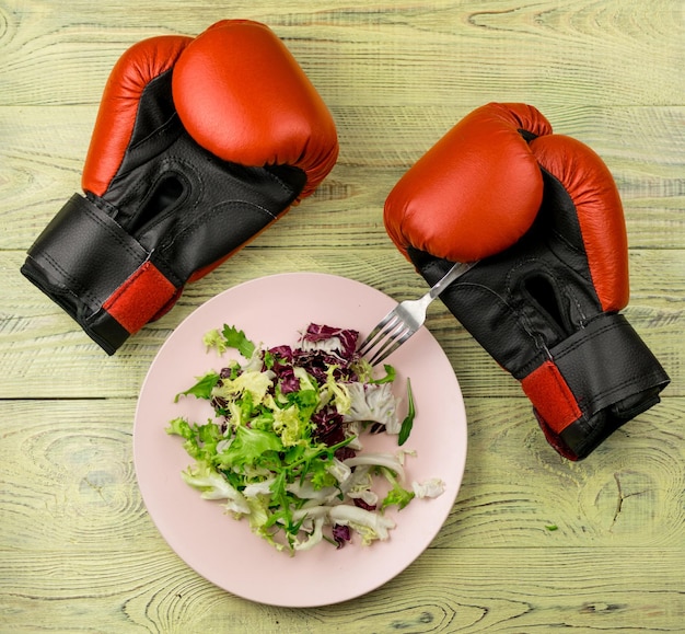 Nutrition for sports healthy active way of life Vegetarian salad of fresh vegetables and boxing gloves on a wooden background