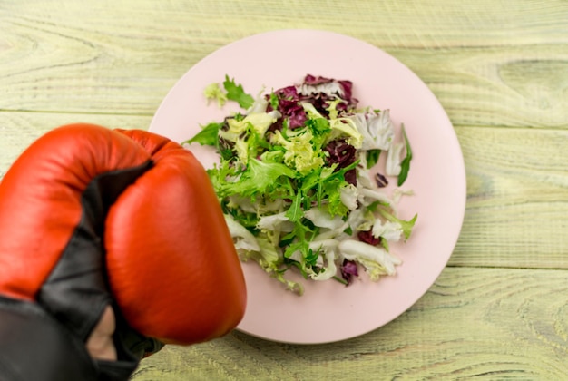 Nutrition for sports healthy active way of life Vegetarian salad of fresh vegetables and boxing gloves on a wooden background