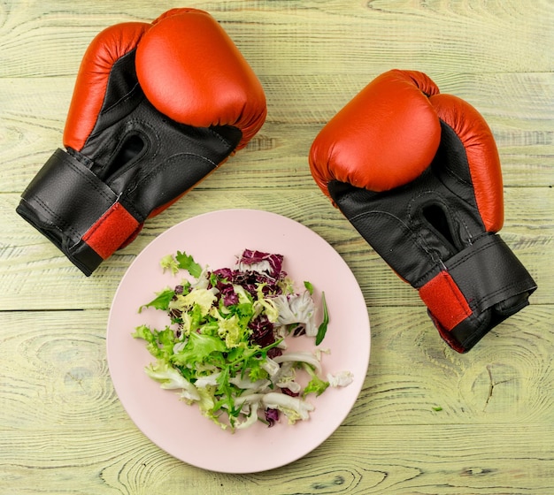 Nutrition for sports healthy active way of life Vegetarian salad of fresh vegetables and boxing gloves on a wooden background