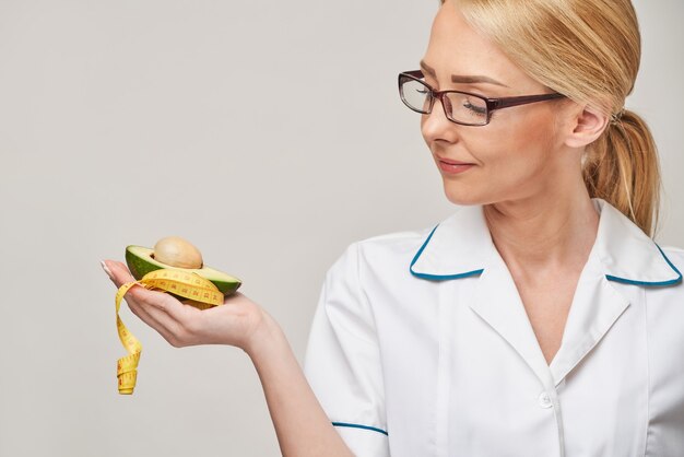 nutritionist doctor healthy lifestyle concept - holding organic avocado fruit and measure tape