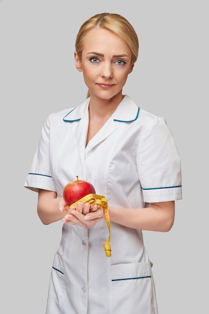 nutritionist doctor healthy lifestyle concept - holding organic red apple and measure tape