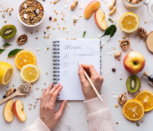 Nutritionist female hand write in notebook on healthy food background