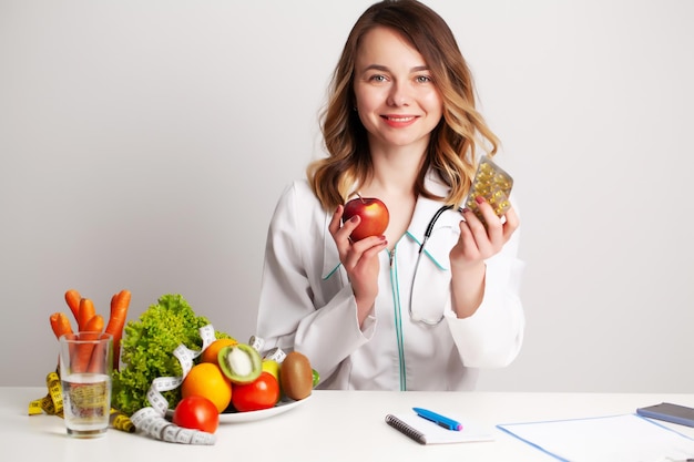 Nutritionist holding omega3 fish oil vitamin tablet and fresh fruit