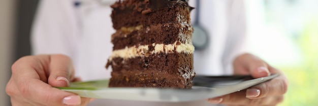 Nutritionist holds plate of chocolate cake in her hands female doctor warns against eating