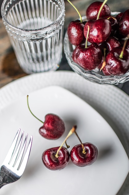 Nutritious cherries with a fork and a glass of water