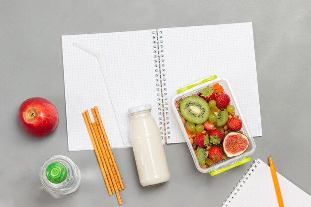 Nutritious lunch box of fruits, berries and nuts, bottle of yogurt and edible straws