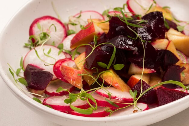 Nutritious salad of sliced boiled beets, sliced radish and apples with young microgreen sprouts.