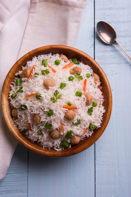 Foto nutriente pulao di soia o pilaf o riso fritto a pezzi di soia con piselli e fagioli. servito in una ciotola su sfondo colorato o in legno. messa a fuoco selettiva