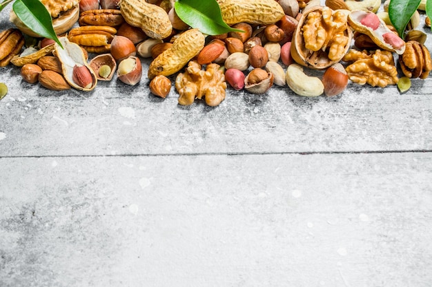 Nuts backgroundAssortment of different types of nuts with green leaves