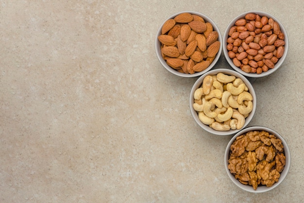 Nuts of different varieties, top view. The mixed nuts lie in bowls on a stone countertop. For design and printing. Place to insert text, recipe or entry.