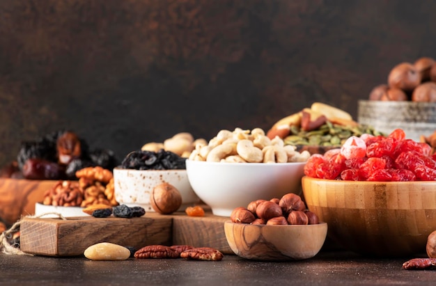 Nuts and dried fruits assortment Healthy snacks Dried apricots figs raisins pecans walnuts hazelnuts almonds and other Brown table background