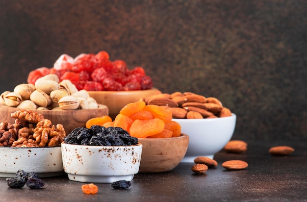 Nuts and dried fruits assortment Healthy snacks Dried apricots figs raisins pecans walnuts hazelnuts almonds and other Brown table background