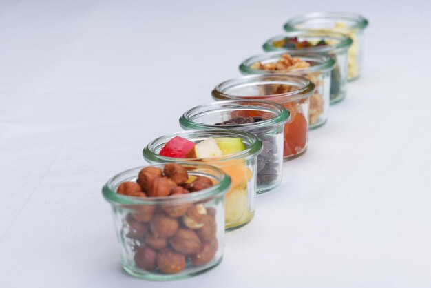 Nuts and dry fruits mix healthy organic food mix in glass bowls isolated on white background