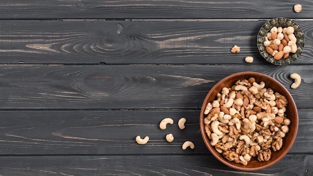 Nuts in the earthen and metallic bowls on black wooden desk