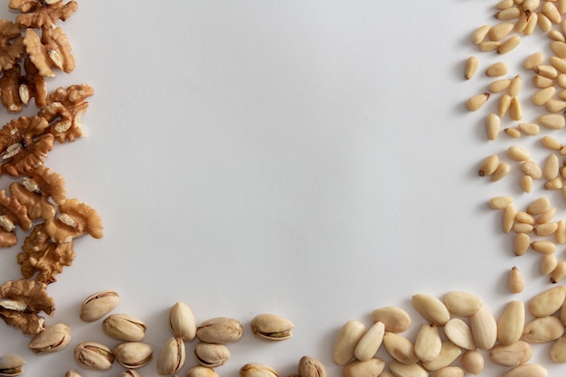 Nuts frame with walnuts, peanuts, almonds and pine nuts on white background. Copy space.