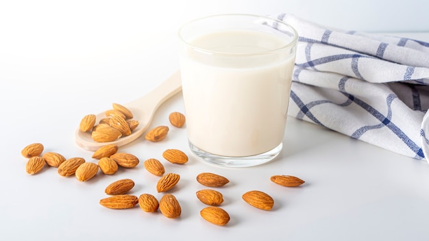 Noci latte e mandorle in bicchieri con panno da cucina sul tavolo bianco