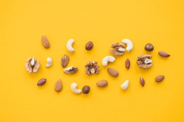 Ореховая смесь для здорового питания кешью, арахис, фундук, грецкие орехи, миндаль на желтом фоне