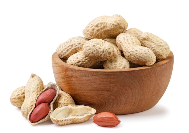 Photo nuts peanuts in a wooden plate and scattered closeup on a white background isolated