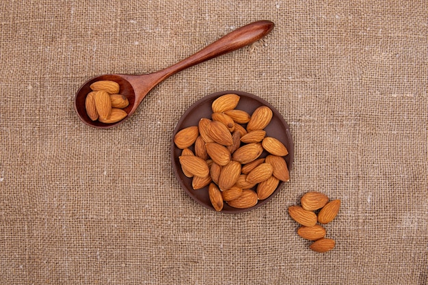 Nuts pistachios in a wooden spoon and a brown earthenware plate on old burlap