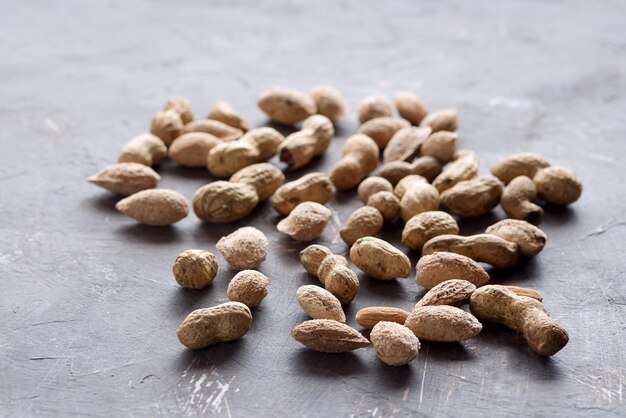 Nuts Unpeeled almonds peanuts and tasty crackers lying on background Copy space