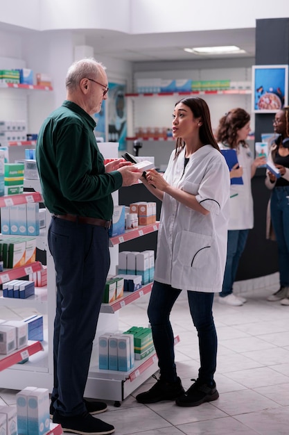 Nuttige apotheker die medisch advies geeft aan senior cliënt tijdens het winkelen van medicijnen in de apotheek, oudere klant die medicijnen, supplementen, vitamine koopt om ziekte te genezen. Medicijnondersteuning