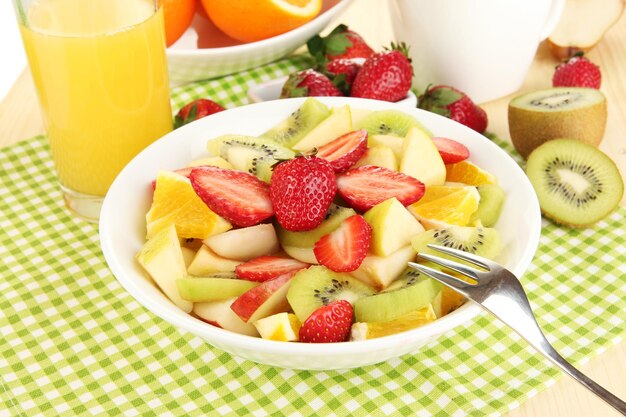 Nuttige fruitsalade van vers fruit en bessen in kom op servet op houten tafel close-up
