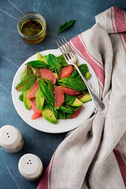 Nuttige smakelijke salade van spinazie, snijbiet, avocado en grapefruit met olijfolie op een oude betonnen donkere achtergrond.