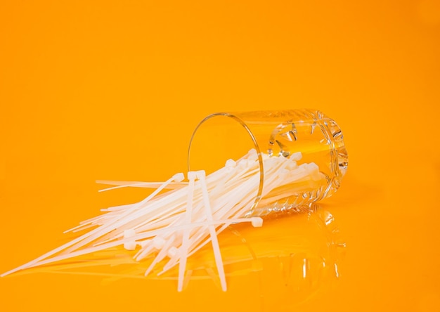 Nylon cable ties in glass in jar in bucket on orange background